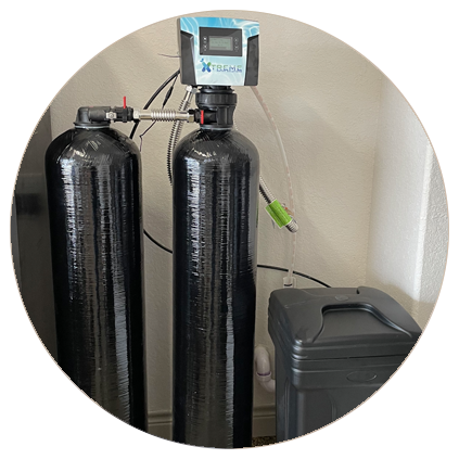 Home water softening system with dual black tanks and digital control valve, installed next to a trash bin.
