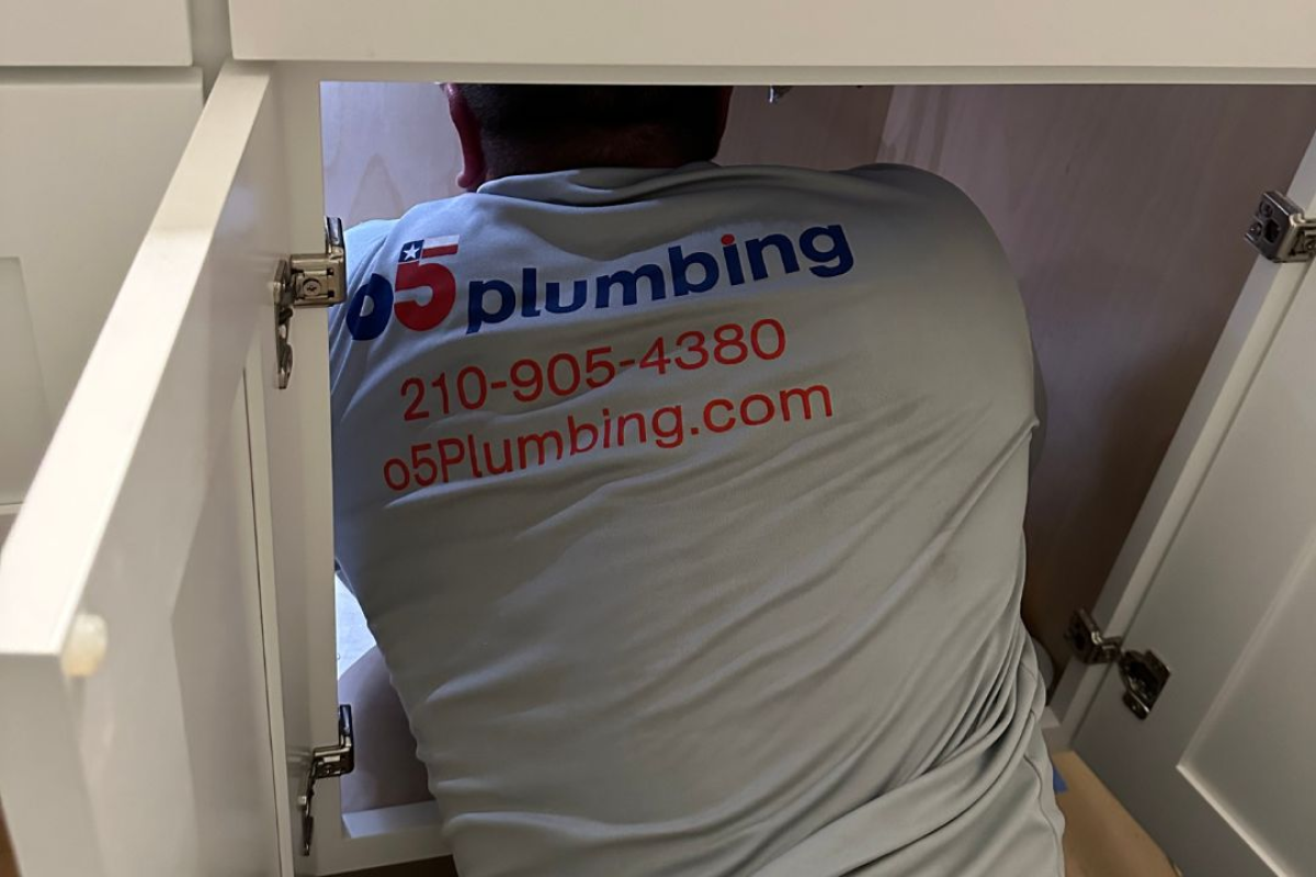 Technician from 05 Plumbing working under a sink.