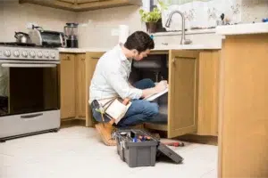 Plumber working under kitchen sink.