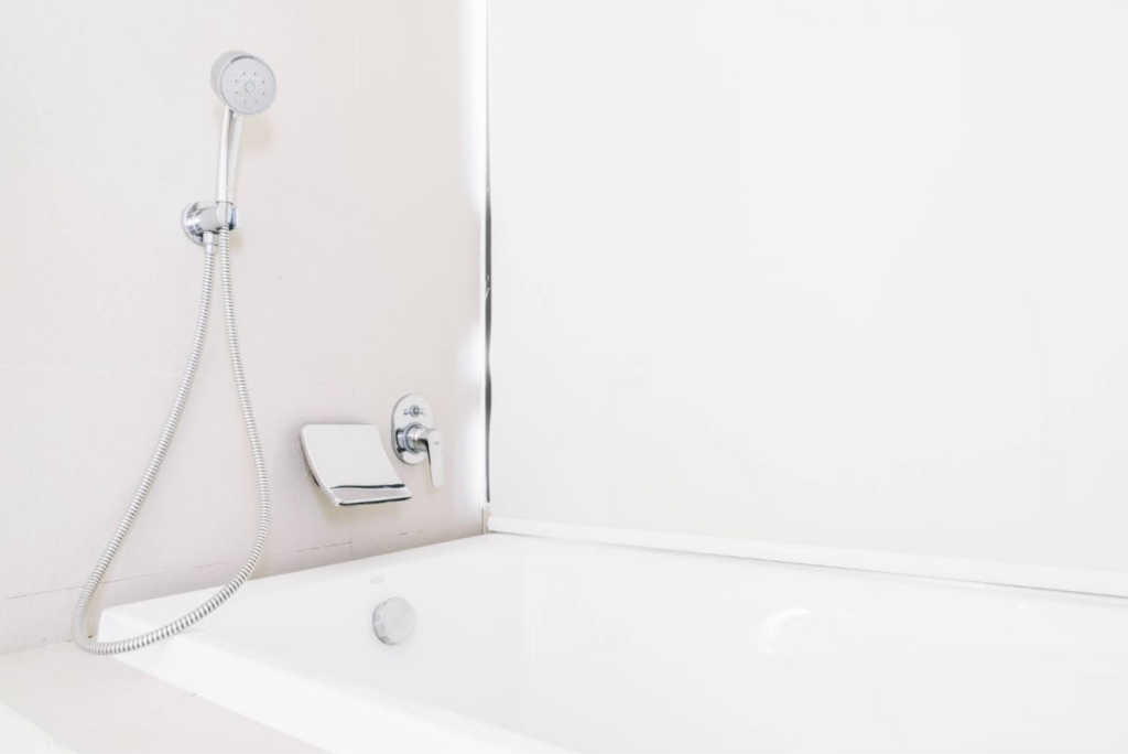 A minimalistic white bathtub with a handheld showerhead mounted on the wall.