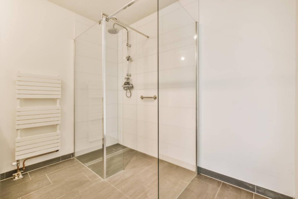 A modern walk-in shower with glass doors and sleek tile flooring in a minimalist bathroom.