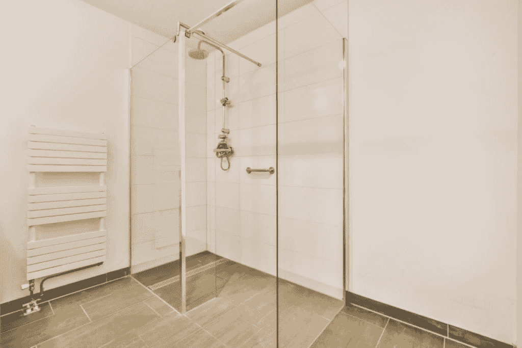 A modern walk-in shower with glass doors and sleek tile flooring in a minimalist bathroom.