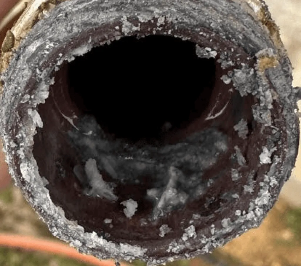 A close-up of a pipe severely clogged with mineral deposits and corrosion, showcasing the need for repiping to ensure clean water flow.