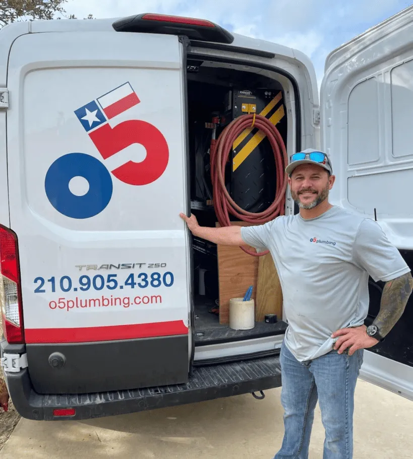 An O5 Plumbing technician standing beside an open service van, equipped with tools and ready for a plumbing job, highlighting professional repiping solutions.