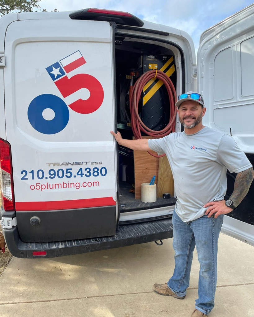 An O5 Plumbing technician standing beside an open service van, equipped with tools and ready for a plumbing job, highlighting professional repiping solutions.