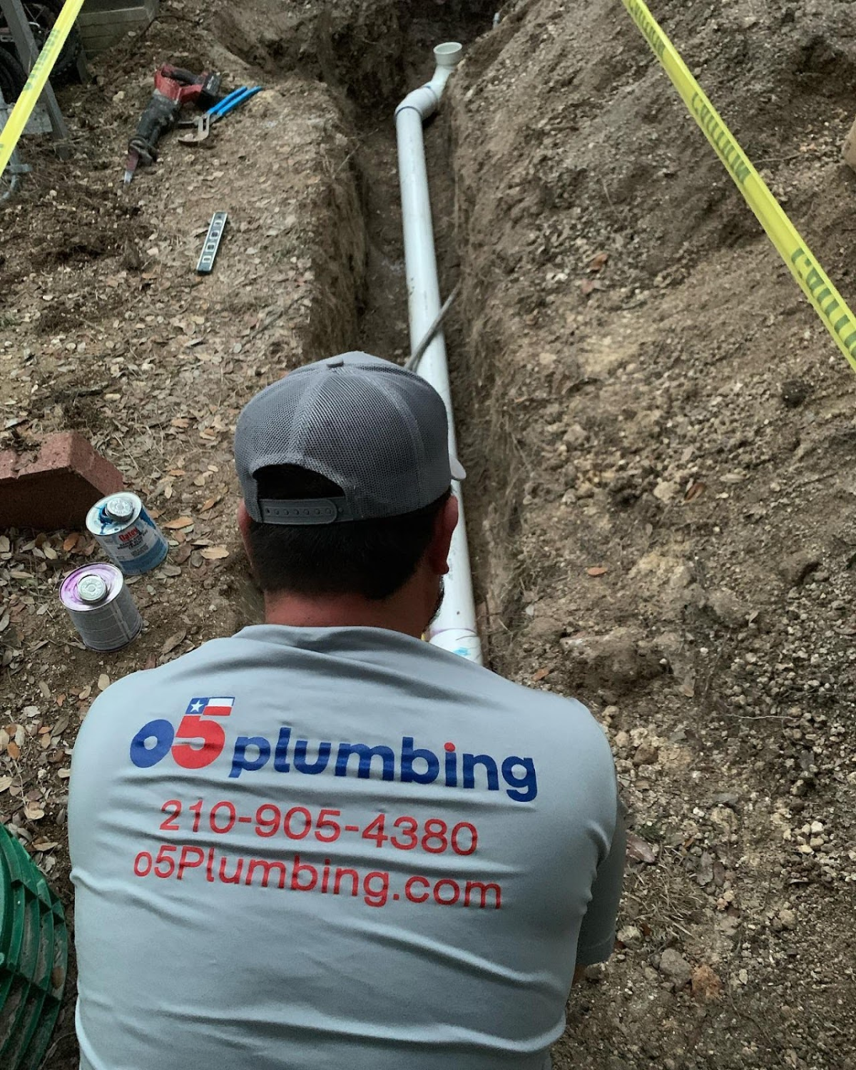 Plumber working on pipe installation in trench.